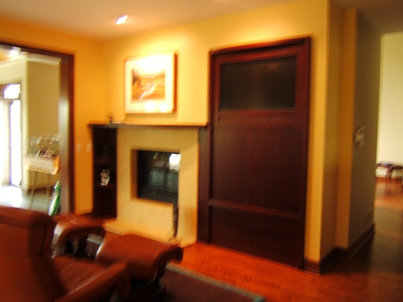 Tall dark wood cabinet doors beside a fireplace in a warm-toned room