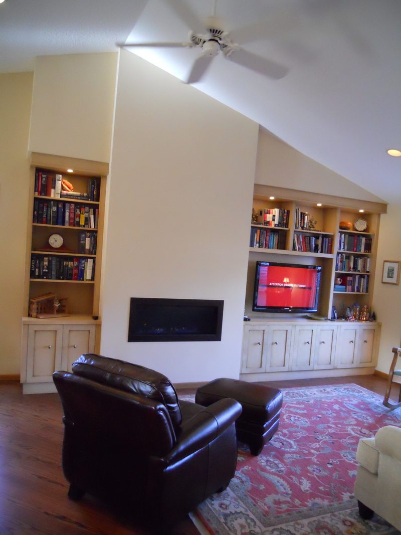 Cream built-in bookshelves and a media cabinet flanking a linear fireplace