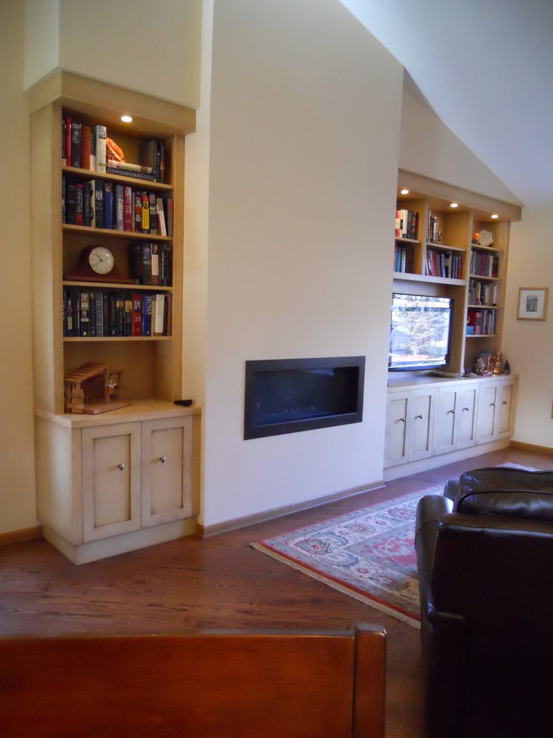 Cream built-in bookcase with lower cabinets next to a linear fireplace