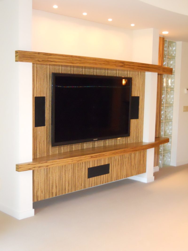 Striped light wood TV wall with floating shelves and speakers