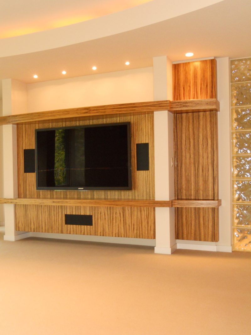 Angled view of a striped wood TV surround beside a glass block wall