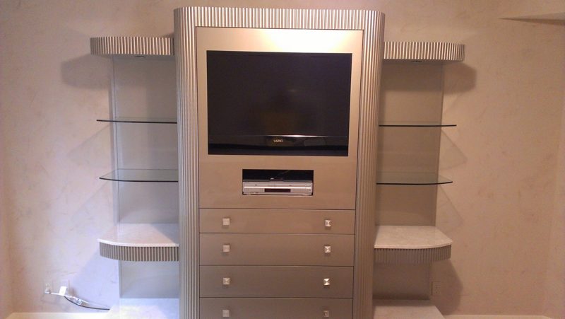 Silver media tower with drawers flanked by glass shelves on curved supports