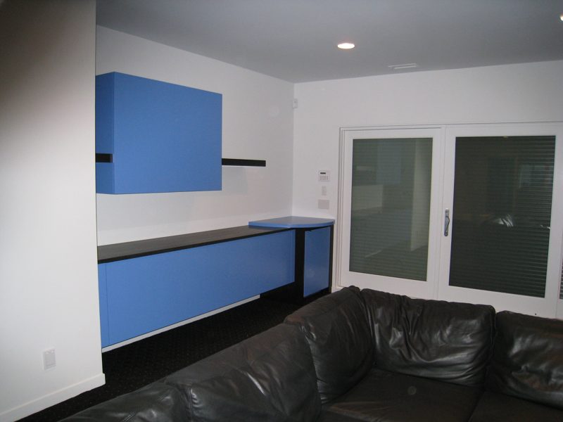 Blue wall cabinets and a floating dark shelf above long blue base cabinets