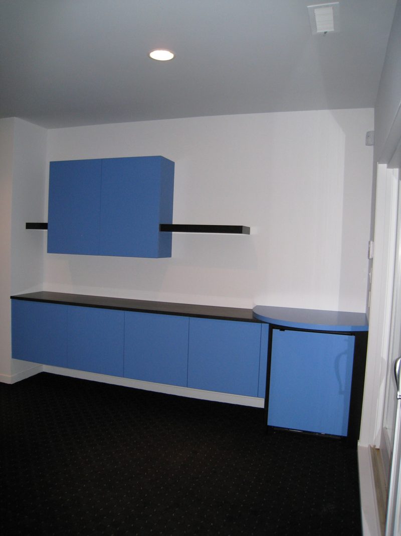 Blue upper cabinet and floating shelf over blue base cabinets with a rounded end