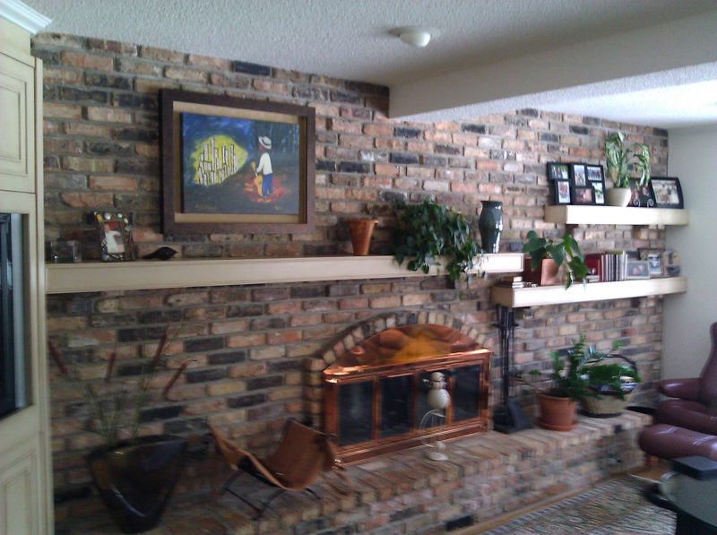 Light floating shelves along a brick fireplace wall