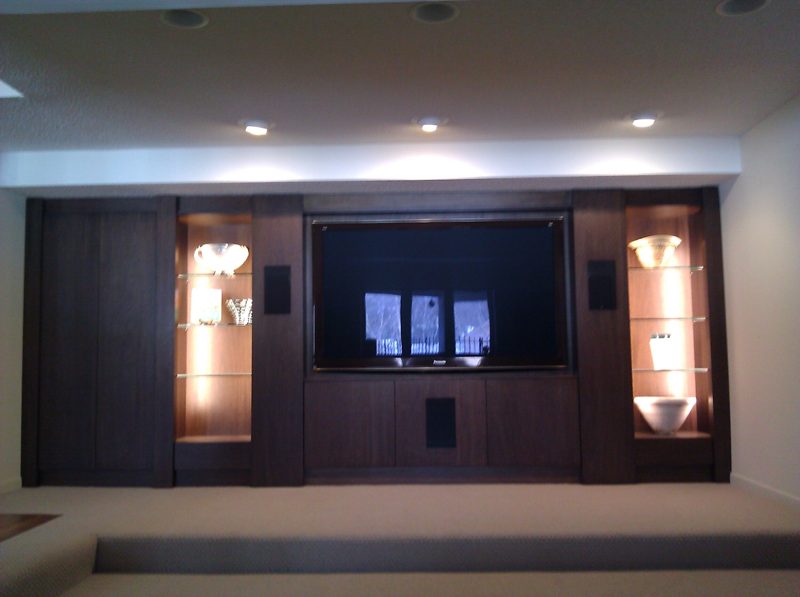 Dark wood media wall with lit display cabinets flanking a TV