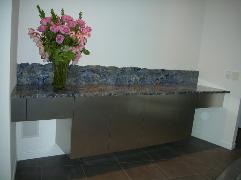 Floating brushed metal cabinet with a blue stone countertop and backsplash
