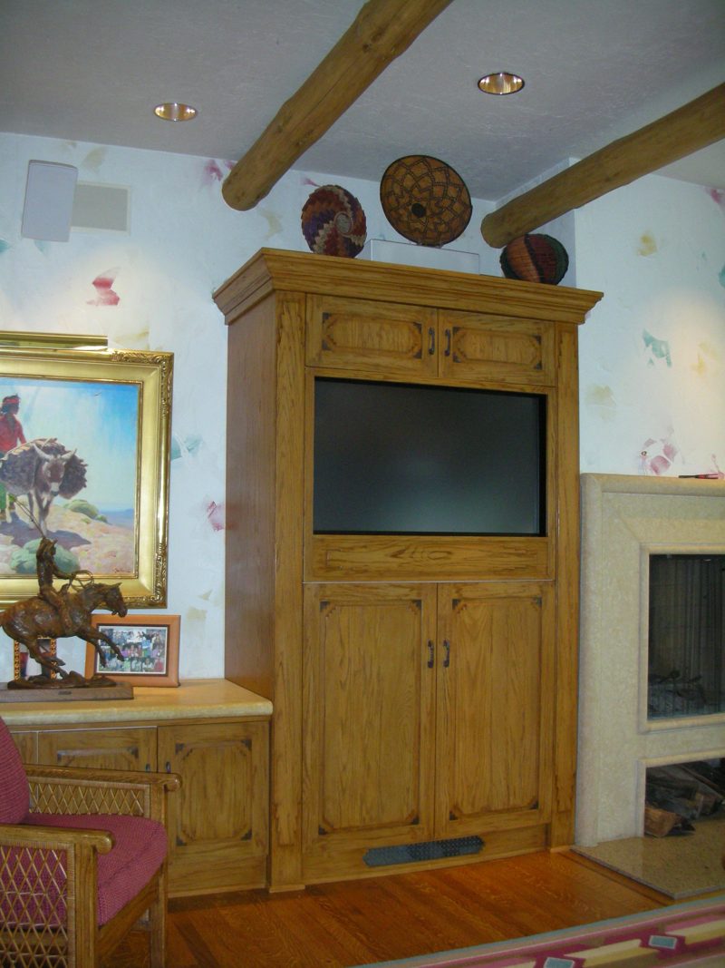Rustic wood armoire-style TV cabinet beside a fireplace