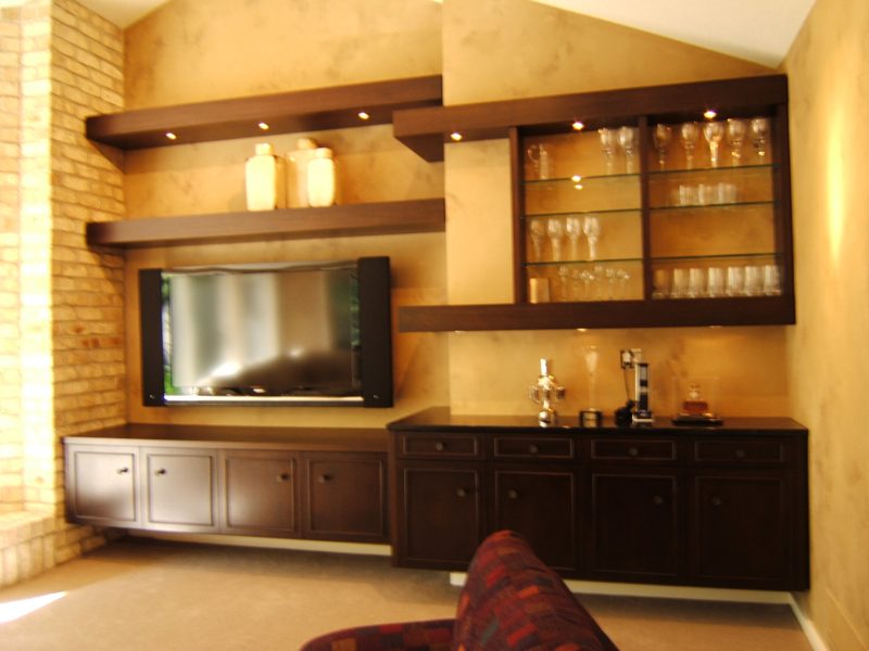 Dark wood floating shelves and low cabinets around a TV and glass cabinet