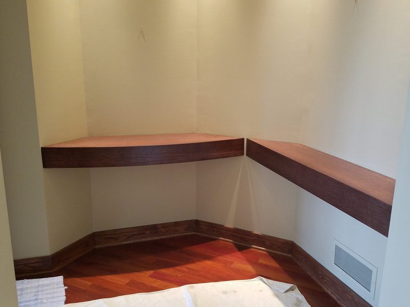 Floating L-shaped wood bench wrapping a corner alcove