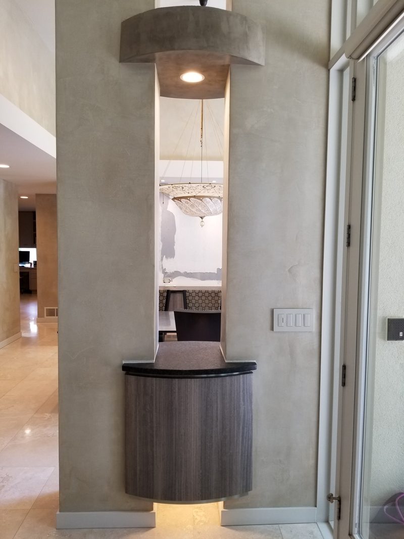 Floating gray console lit from below inside a column niche