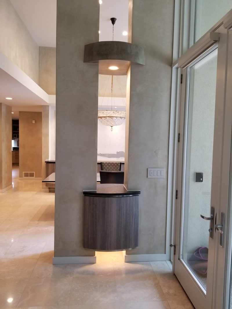 Entry hall column with a floating gray cabinet and a lit niche
