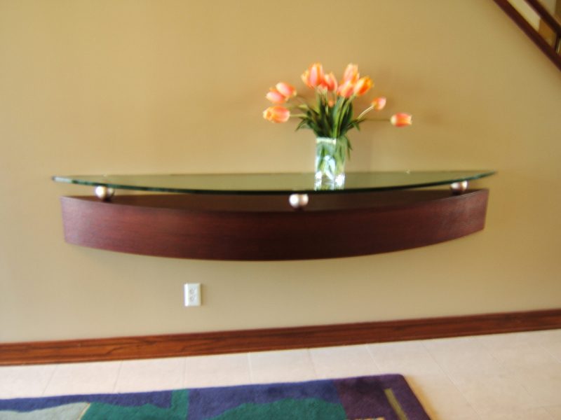 Floating curved wood shelf with a glass top in a stairway hall