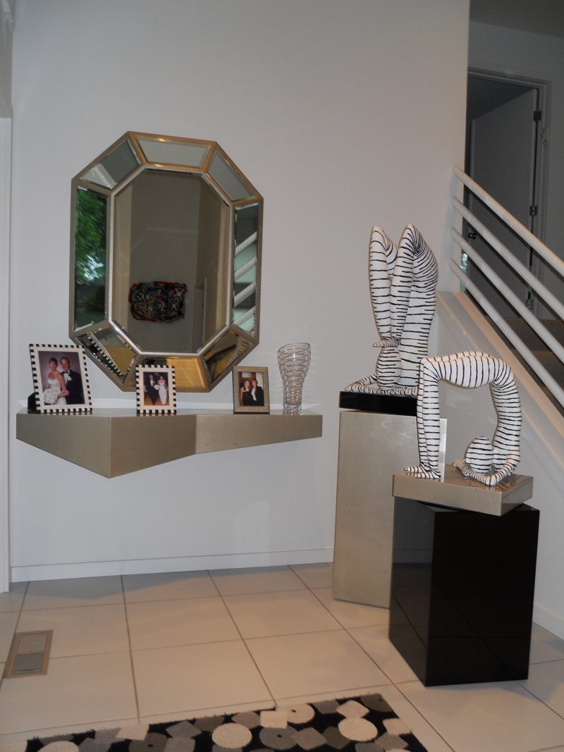 Floating champagne-finish console below an octagonal mirror in a tiled entry