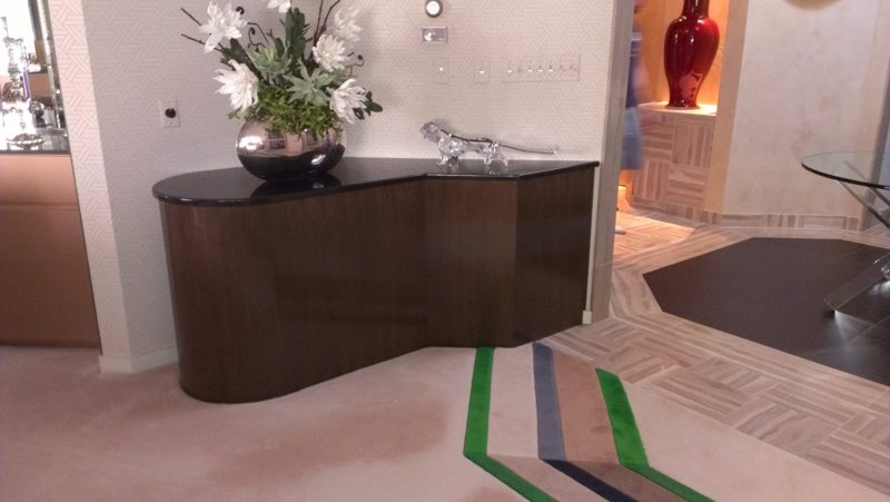 Curving dark wood console with a black top and a flower arrangement