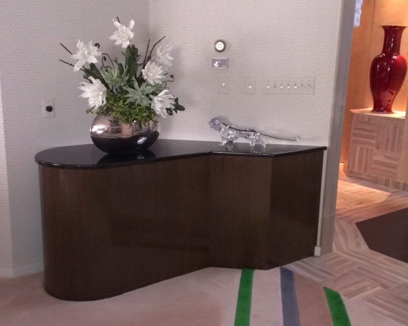 Close view of a wavy dark wood console with a black top