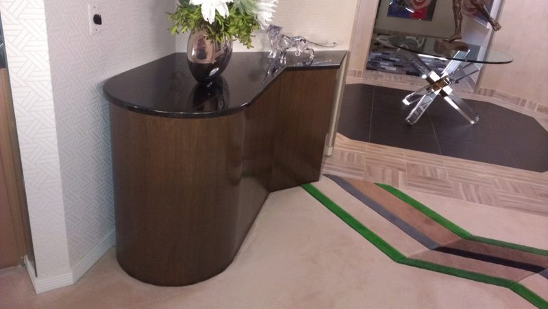 Side view of a curved dark wood console on a patterned carpet