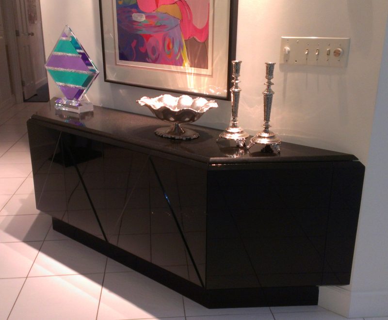 Close angled view of a glossy black sideboard with inlaid door lines