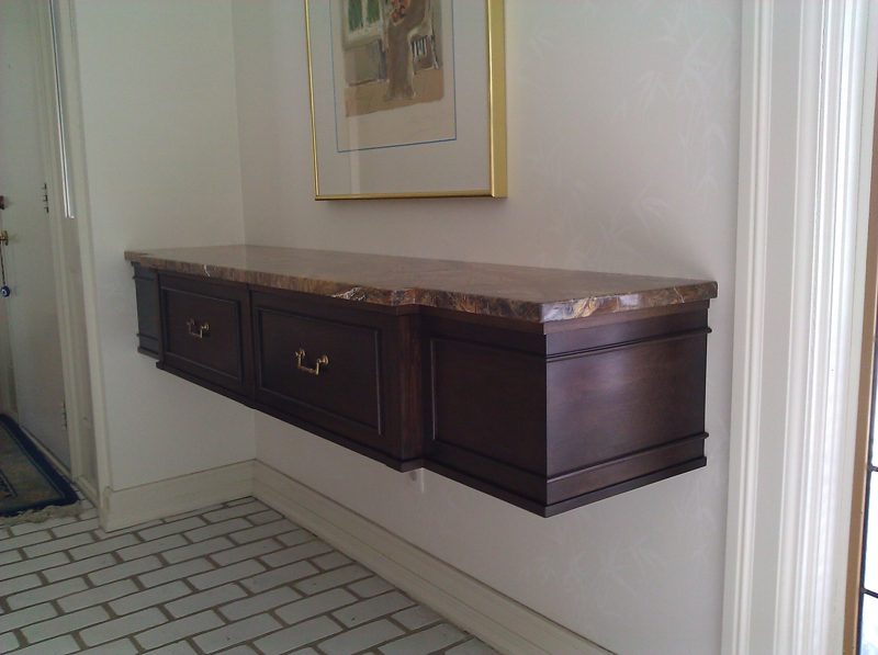 Angled view of a dark wood wall-hung console with a marble top