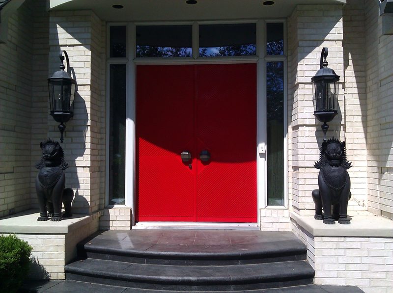 Glossy red double front doors between lanterns and lion statues