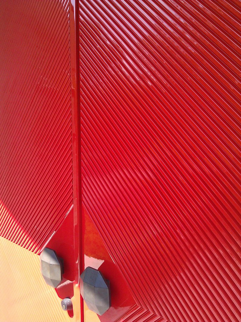 Close view of diagonal grooves and hardware on glossy red doors