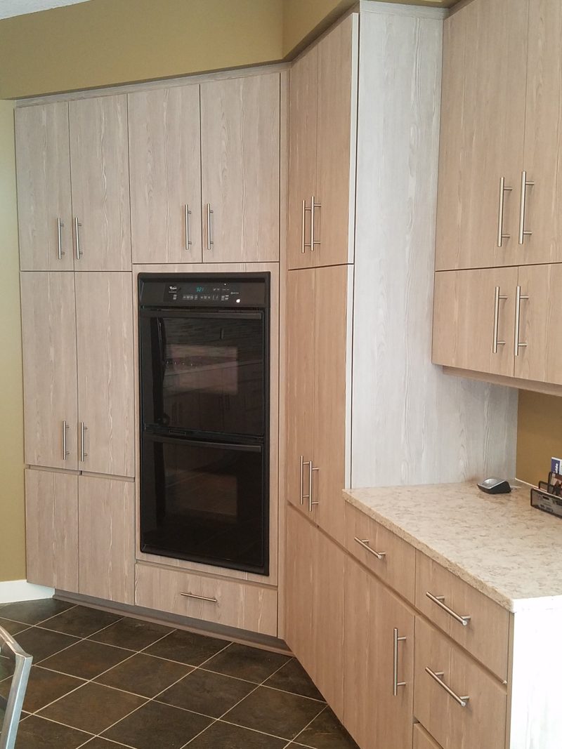 Tall light oak-grain cabinets with double wall ovens beside a corner counter