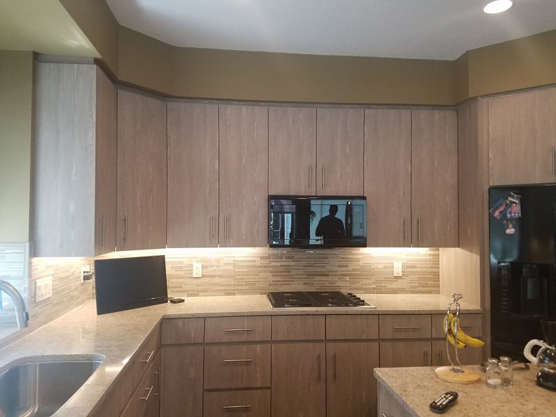 L-shaped counter of light oak-grain cabinets with under-cabinet lighting and a cooktop