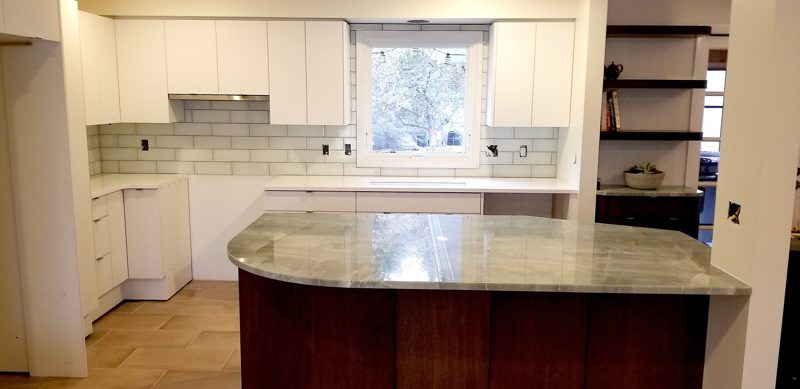 White kitchen with a dark wood island and granite top below a window