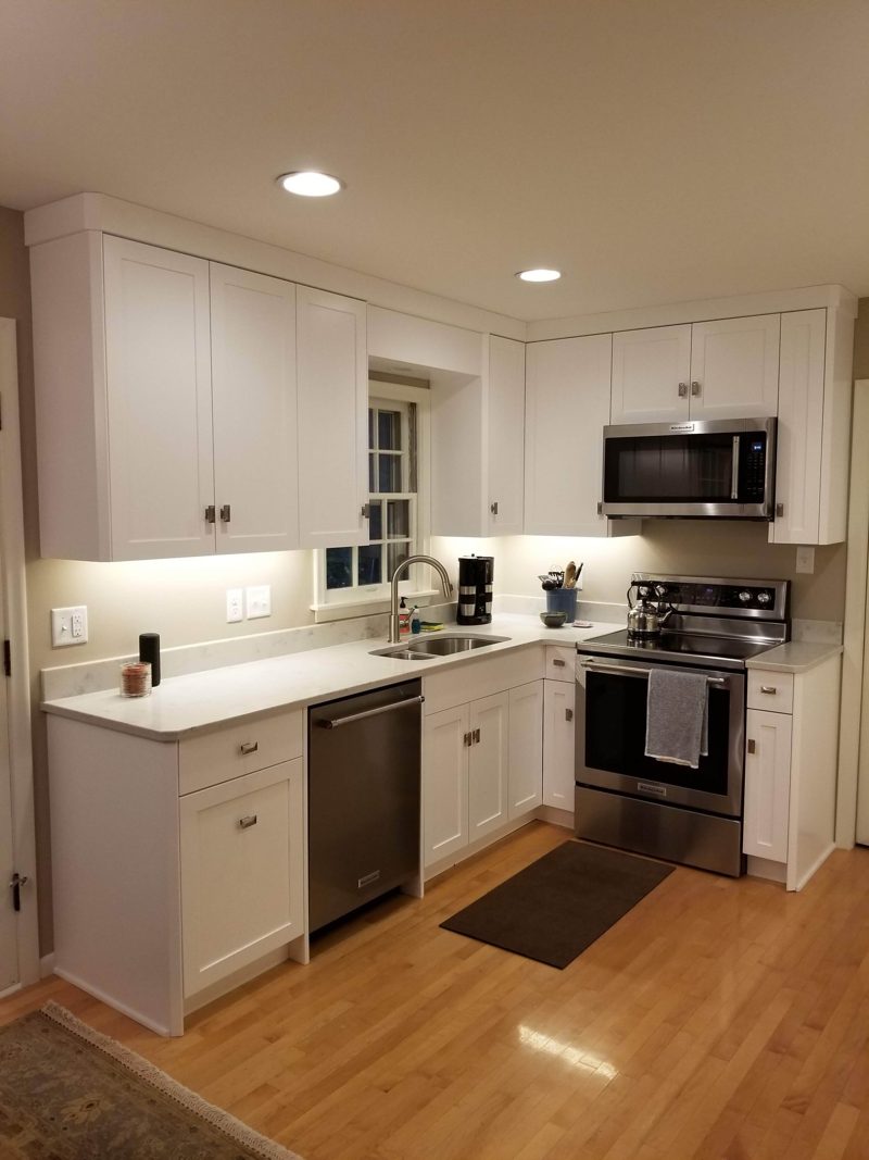 White shaker kitchen with a stainless range and microwave on a wood floor