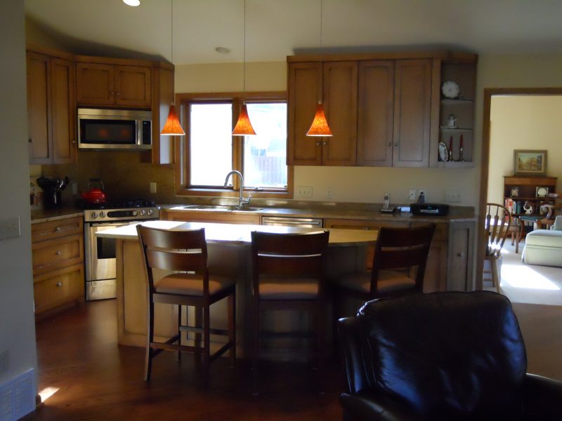 Wood kitchen with an island and stools under orange pendant lights