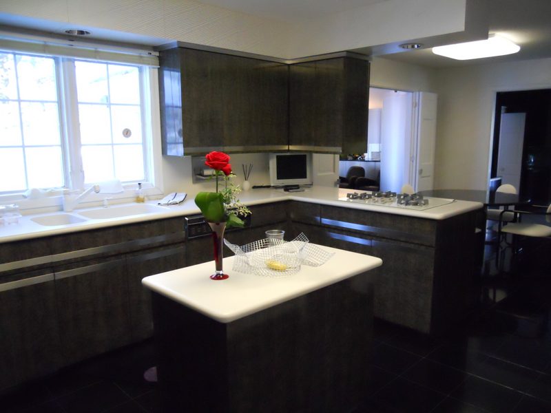 Dark gray cabinetry with a white island holding a single red flower