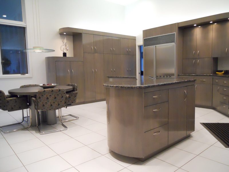 Taupe cabinetry with a curved island, stainless refrigerator, and white tile floor