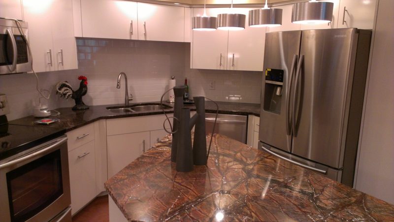 White kitchen with a red-veined granite island and stainless refrigerator
