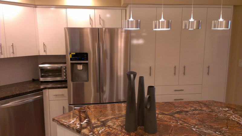 White kitchen with pendant lights over a red-veined granite island
