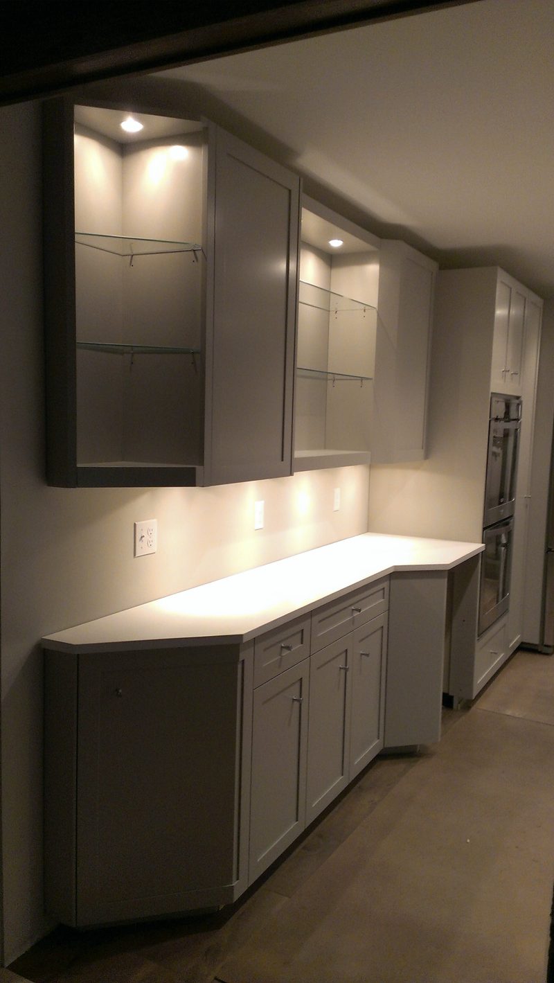 Gray cabinets with lit glass-front uppers and under-cabinet lighting