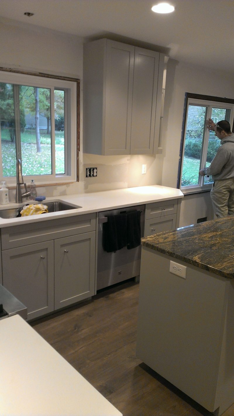 Gray kitchen sink under a window with a granite island in front