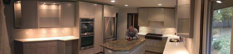 Panoramic view of a gray kitchen with an island and wall ovens
