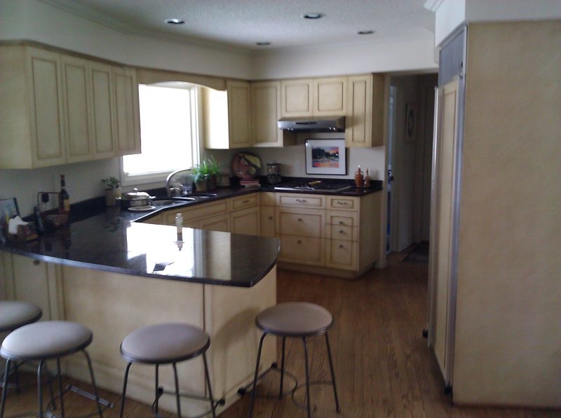 Cream cabinetry with a black granite peninsula and bar stools