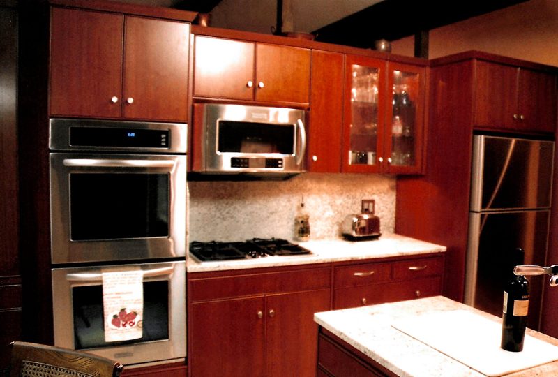 Cherry cabinetry with stacked wall ovens and a white island
