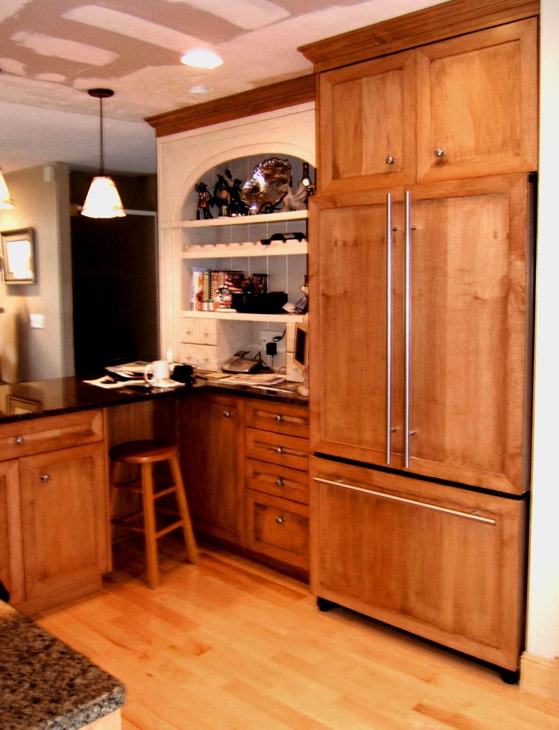 Maple refrigerator panels beside a white built-in hutch and desk