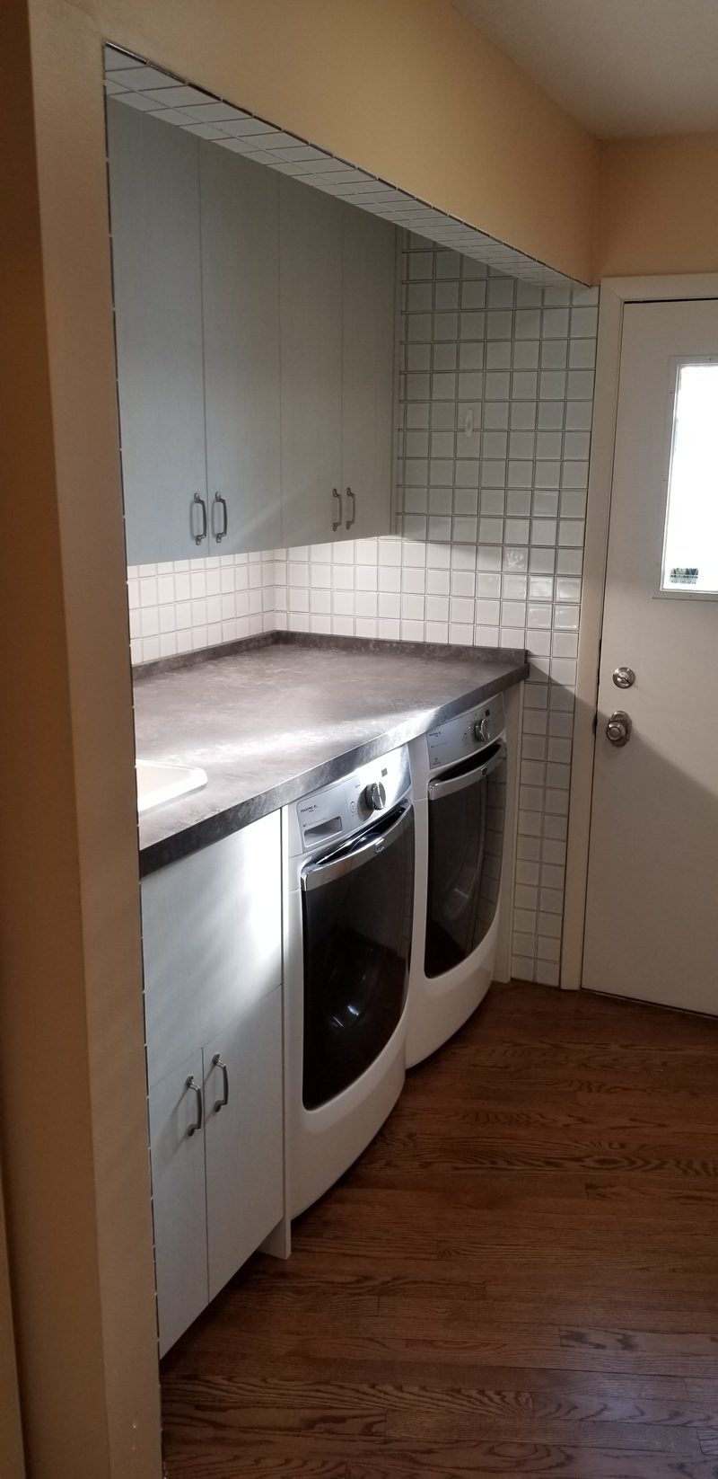 Laundry room with taupe cabinets, a dark countertop, and front-load machines