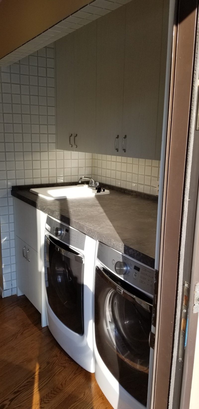 Taupe upper cabinets over a dark countertop and front-load washer and dryer
