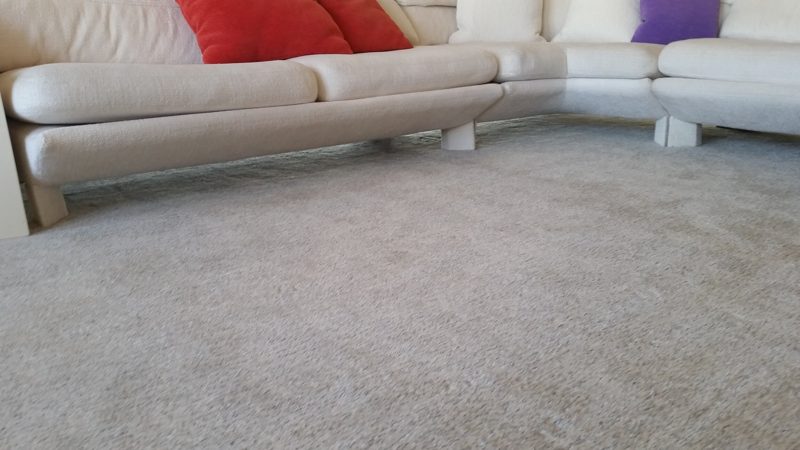 Cream sectional sofa with red and purple pillows on a light carpet