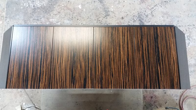 Striped dark wood tabletop with angled ends on a shop floor