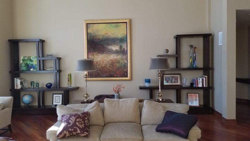 Dark wood floating shelves flanking a painting above a cream sofa