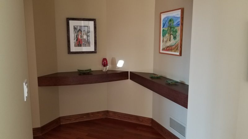 Dark wood floating corner shelves in a living room nook