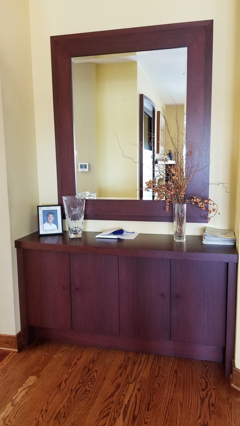 Dark cherry cabinet below a large dark wood framed mirror