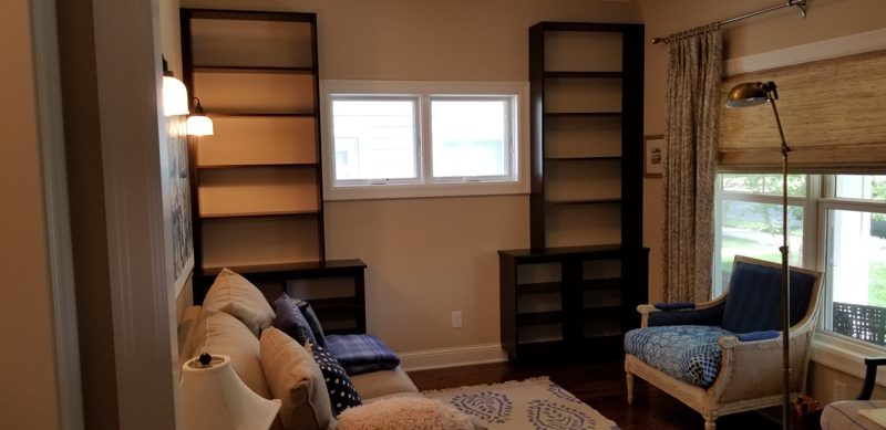 Dark wood bookcases on either side of a window in a sitting room