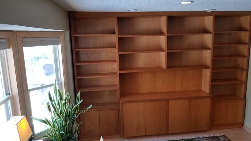 Wood built-in wall of open bookshelves over lower cabinets
