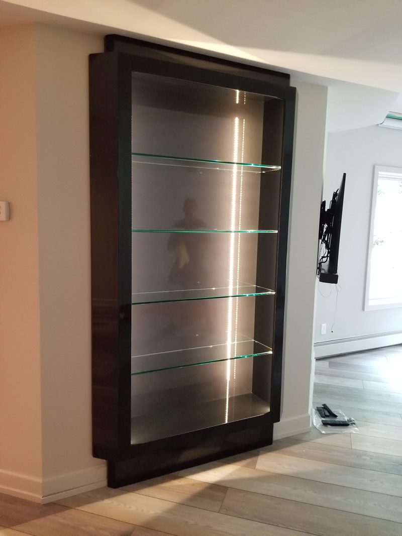 Dark wood recessed display case with glass shelves and side lighting